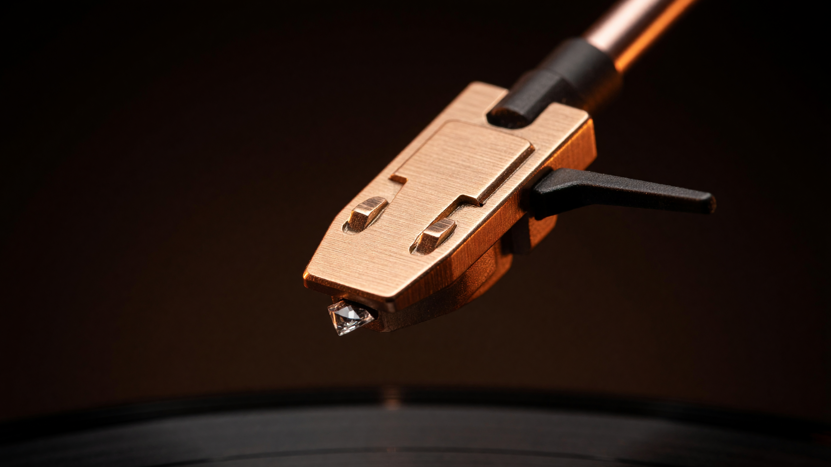 Close-up of the copper tonearm and diamond-tipped needle